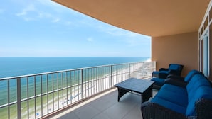 Un balcon avec vue sur l’océan, une table et des chaises bleues.