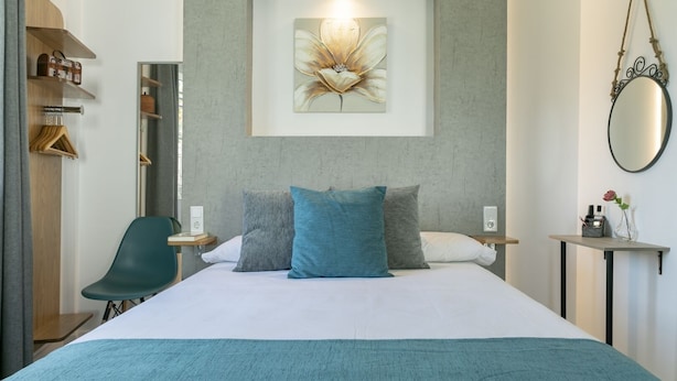 Una habitación de hotel moderna con una cama grande, un escritorio, una silla y un espejo montado en la pared.