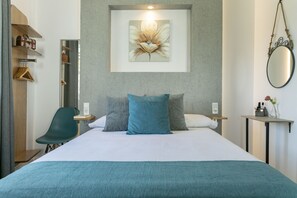 A modern hotel room with a large bed, a desk, a chair, and a wall-mounted mirror. - Montesa 3 (Málaga)