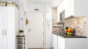 Una cocina moderna con armarios blancos, salpicadero de ladrillo y un bol con fruta en la encimera.