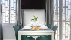 Comedor con una mesa dispuesta para cuatro, incluyendo platos, vasos y un pequeño arreglo floral.