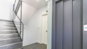 Una escalera con barandillas metálicas que conduce a una puerta con un letrero de salida verde.