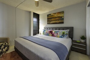 Un dormitorio con cama, mesita de noche, un cuadro en la pared y una ventana con persianas.