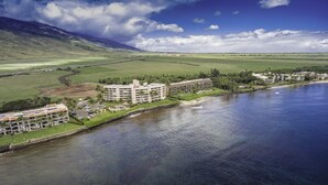 Ein Küstenhotel mit mehreren Gebäuden, einem Strand und einer Bergkulisse.