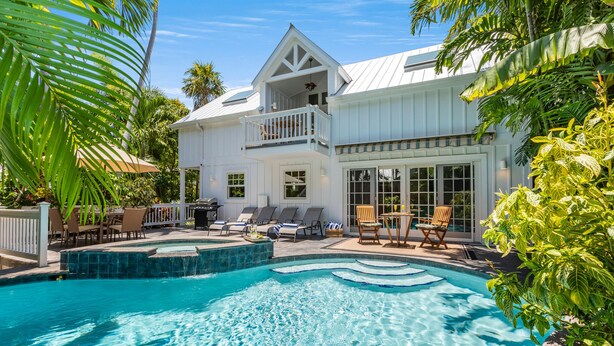 Une grande maison dotée d’une piscine, d’un balcon et d’un patio aménagé avec des chaises et des tables.
