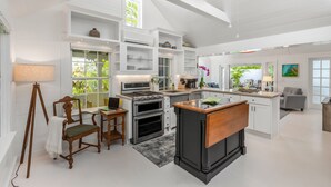 Een moderne keuken met witte kasten, een centraal eiland en ingebouwde apparatuur.