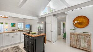 Een moderne keuken met witte kastjes, een zwart kookeiland en een groot raam.