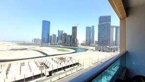A view of a modern cityscape with high-rise buildings, a marina, and a road leading to a beach. - Pristine Studio with Canal View - 703 (Abu Dhabi)