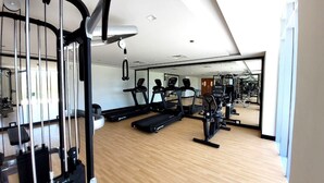 A gym with treadmills, exercise bikes, and weight machines. - Pristine Studio with Canal View - 703 (Abu Dhabi)