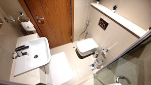 A bathroom with a white sink, toilet, and shower area. - Pristine Studio with Canal View - 703 (Abu Dhabi)