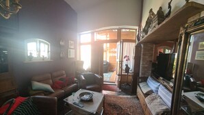 A cozy living room with a sofa, armchairs, a coffee table, and a television. - Renovierte Scheune mit Historischem Charme (Garz/Rügen)