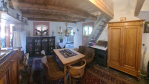 A rustic room with a wooden table, chairs, a chandelier, and a large wooden cabinet. - Renovierte Scheune mit Historischem Charme (Garz/Rügen)