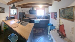 A kitchen with a wooden ceiling, a sink, a microwave, and a coffee maker. - Renovierte Scheune mit Historischem Charme (Garz/Rügen)