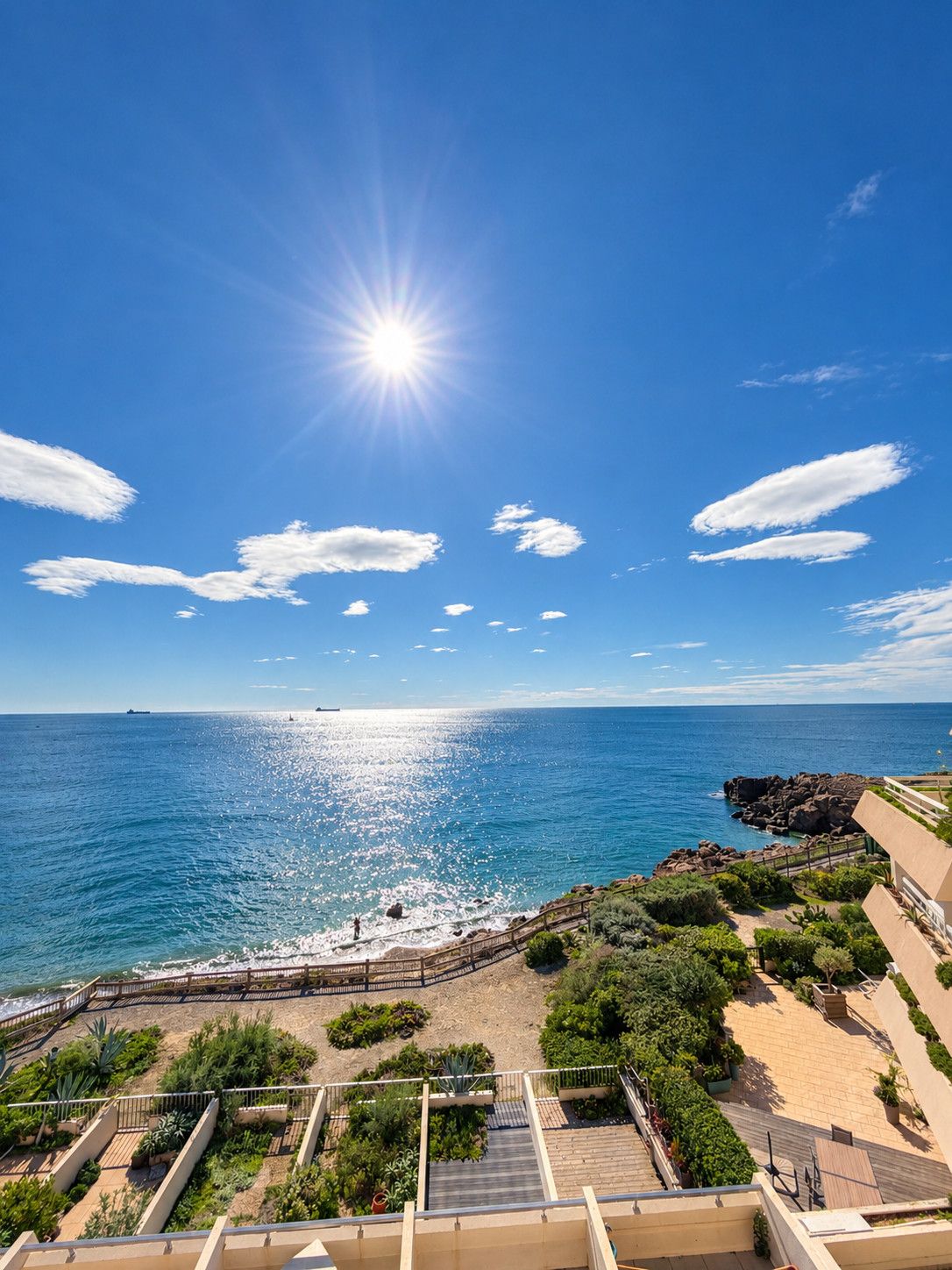 Une vue sur la côte, avec un ciel dégagé, un soleil éclatant et une côte rocheuse.