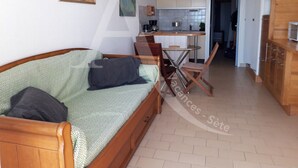 Uma sala de estar acolhedora com um sofá de madeira, uma mesa de jantar e uma área de cozinha com armários e uma pia.