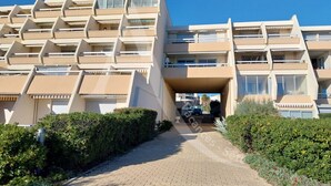 Um edifício com vários andares, um átrio central, varandas e um caminho pavimentado que leva à entrada.