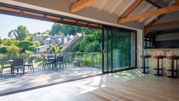 Een ruim terras met uitzicht op een stenen huis en weelderige begroeiing.