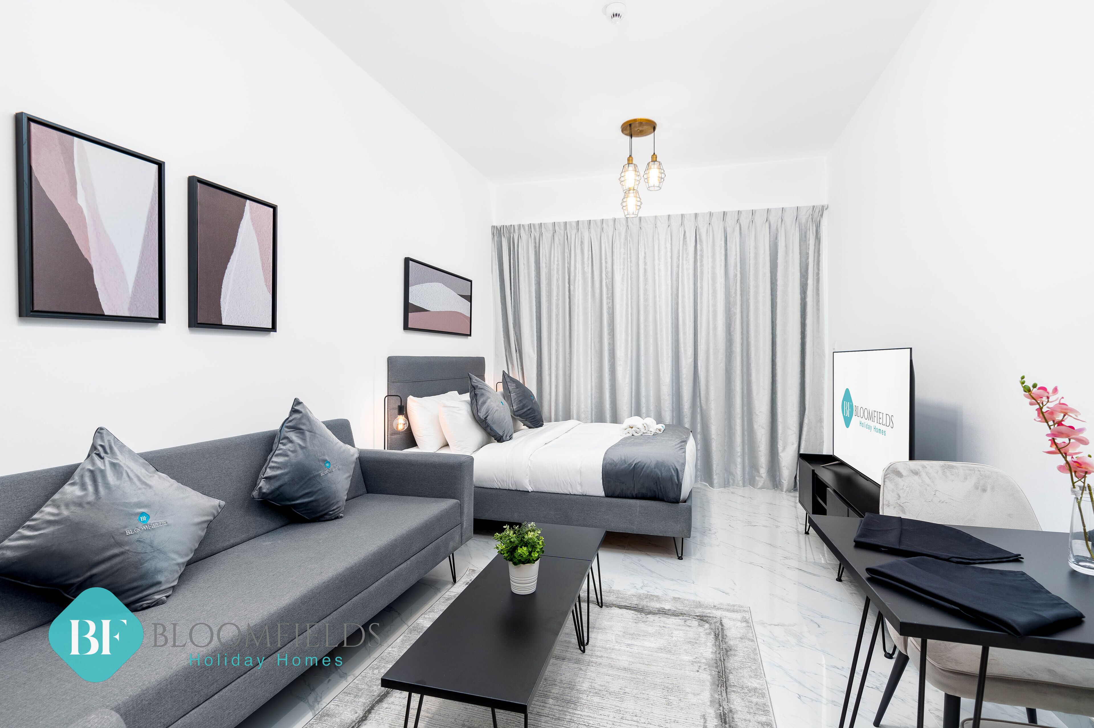 A modern bedroom with a bed, grey sofa, and a coffee table.