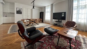A modern living room with a flat-screen TV, leather chairs, a wooden coffee table, and a projector mounted on the ceiling. - Zagreb Center 2BR + 2.5BA - 104m² Loft by Cathedral (Zagreb)