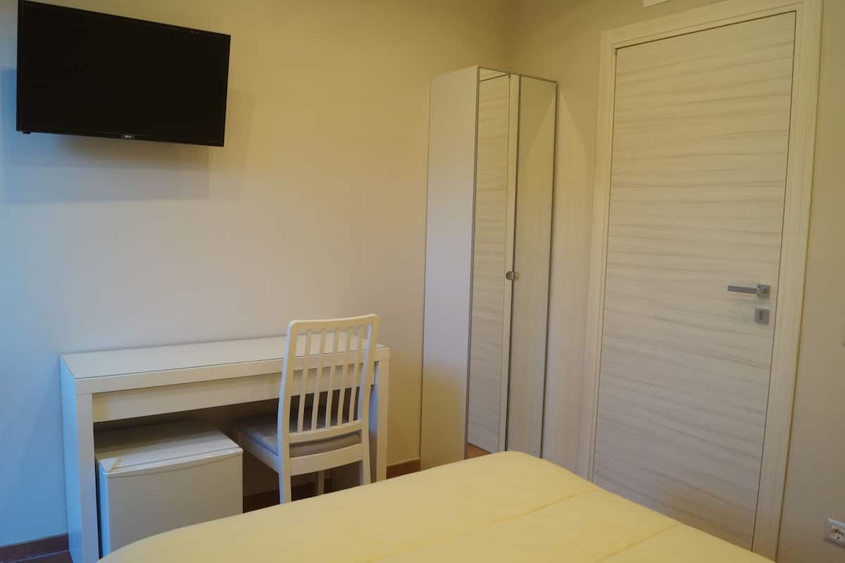 A bedroom with a bed, a desk, a chair, and a wardrobe.