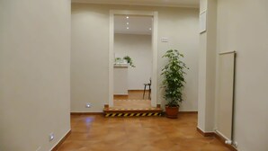 A hallway with a tiled floor, a potted plant, a radiator, and a door leading to another room. - Gialel Pisa Guest House (Pisa)