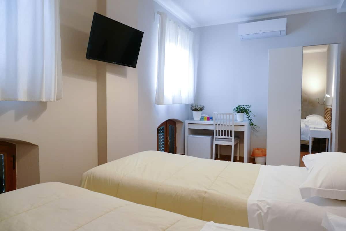 A hotel room with two beds, a desk, a chair, a television, and a mirror.