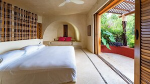 Un dormitorio con cama, ventilador de techo, sofá con cojines y vistas al exterior.
