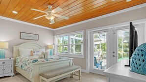 A bedroom with a bed, bedside tables, a bench, and a ceiling fan. - Beached Inn 3 Bedroom Home by RedAwning (Holmes Beach)