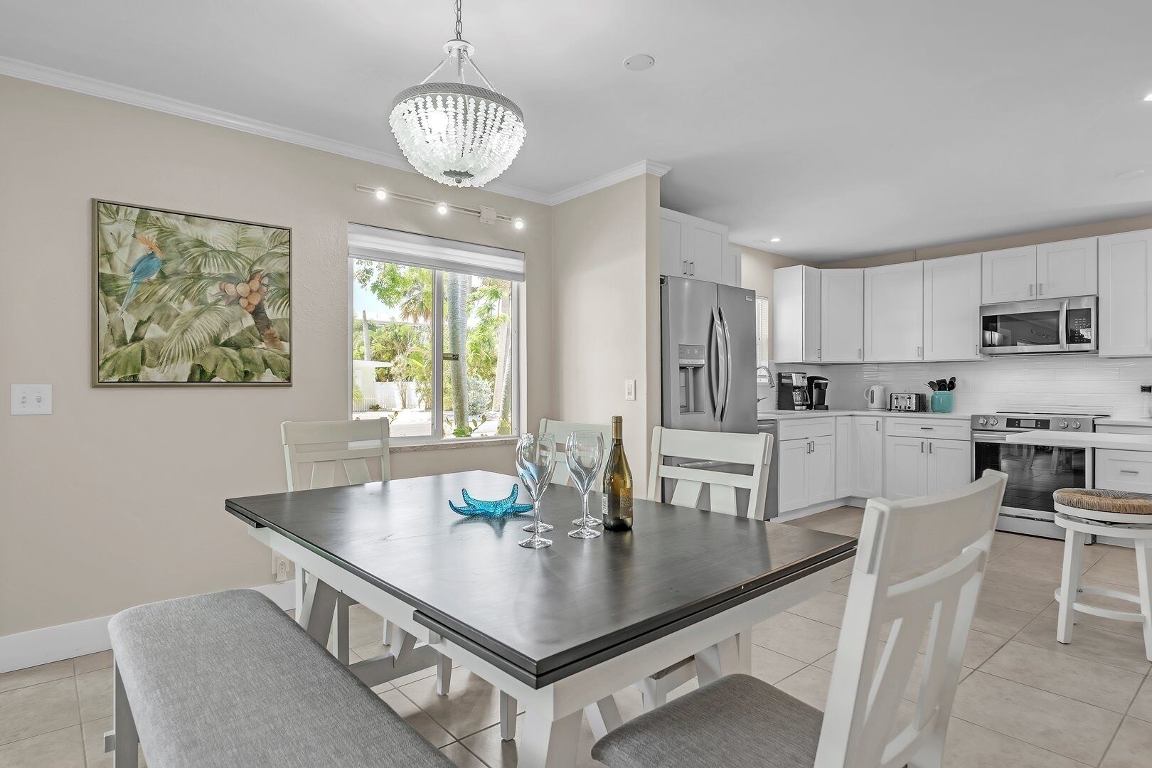 A modern kitchen with white cabinets, stainless steel appliances, and a dining area with a table set for two.