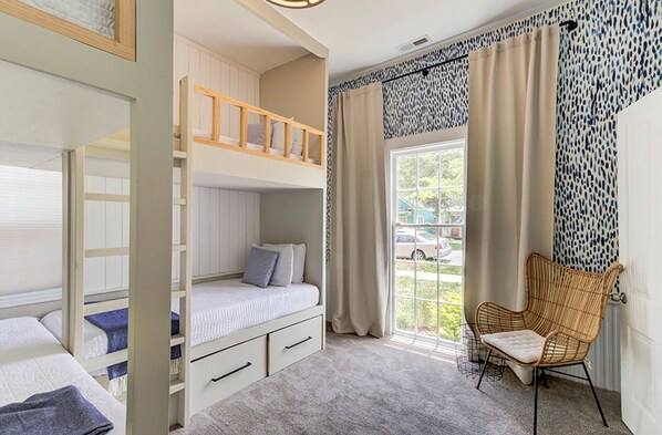 A room with bunk beds, a chair, and a window with curtains. - Brooklyn Arts Cottage (Wilmington)