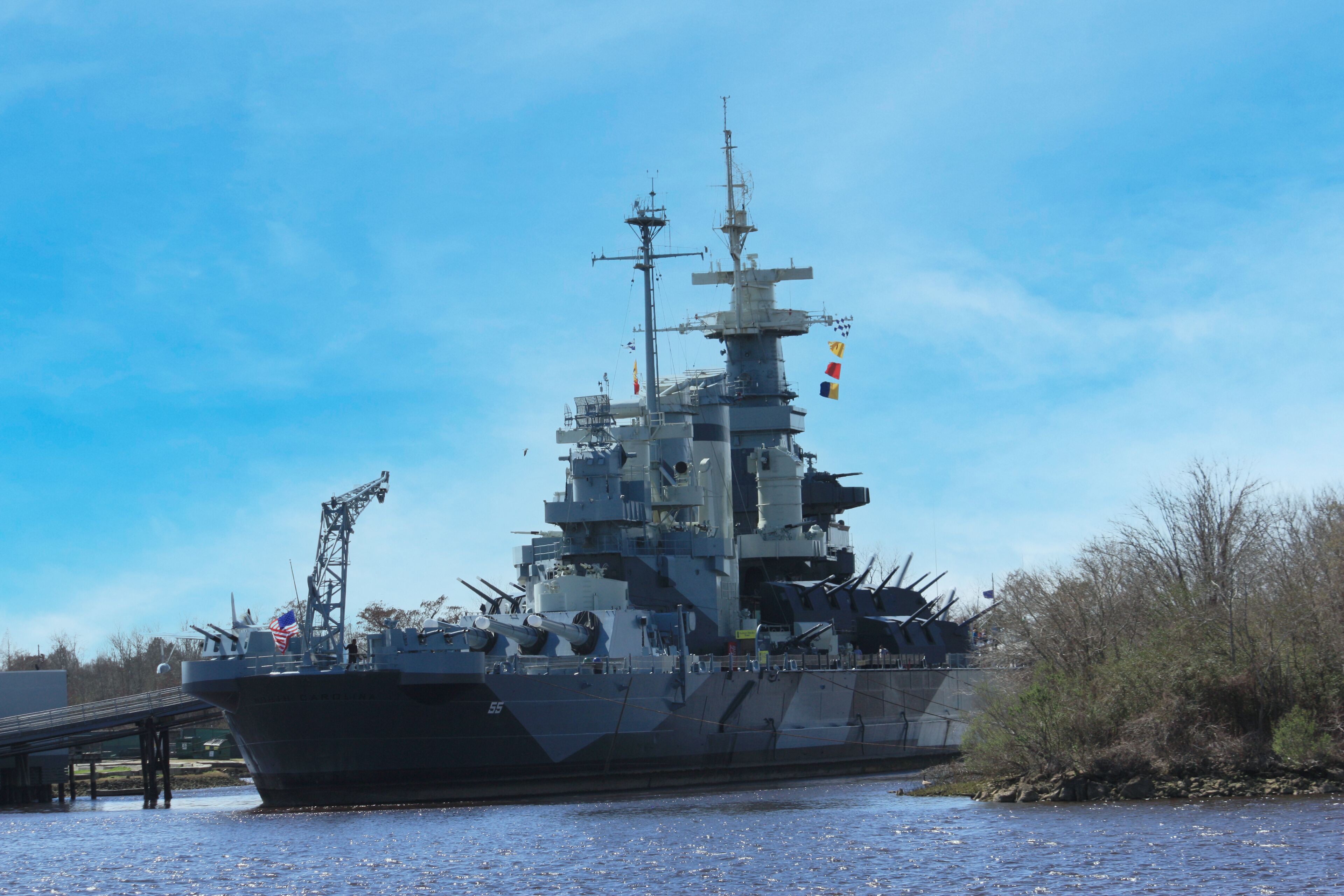 A large military ship docked at a pier.