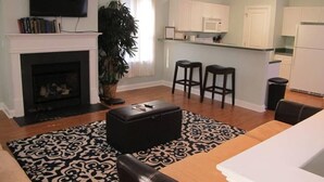 A living room with a fireplace, a television, and a kitchen area with bar stools. - Loft on 3rd 616: 2  BR, 2  BA Condominium in Wilmington, Sleeps 4 (Wilmington)