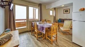 A compact living space with a dining area, kitchenette, and a sofa. - Les Olympiades by Interhome (Val Thorens)