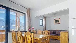 A dining area with wooden chairs and a table, a sofa, and a refrigerator. - Les Olympiades by Interhome (Val Thorens)