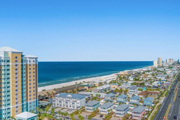 A coastal town with beachfront properties, a high-rise hotel, and a clear blue sky.