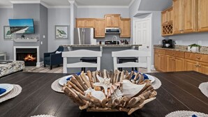 Une cuisine moderne avec des meubles en bois, un îlot central et un coin repas agrémenté d’une pièce maîtresse originale.