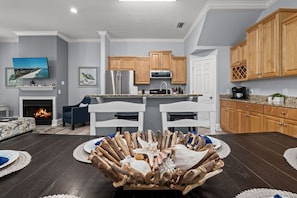 A modern kitchen with wooden cabinets, a central island, and a dining area with a unique centerpiece.