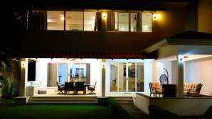 Una casa de dos pisos con un patio que incluye muebles de exterior y una mesa de comedor.