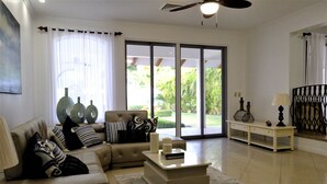 Amplia sala de estar con sofá color beige, una mesa de centro y un gran ventanal corredero que da a un balcón.