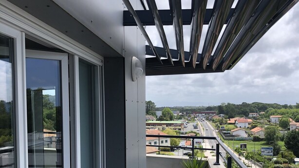 A balcony with a view of a residential area, a potted plant, and a metal railing. - Appartement Idéal Découverte Landes Pays Basques (Tarnos)