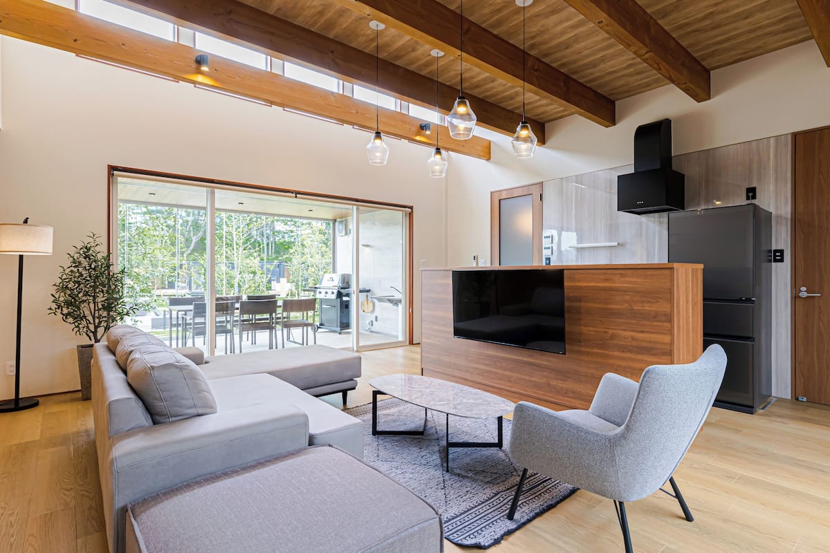 A modern living room with a sectional sofa, a grey armchair, and a flat-screen TV.