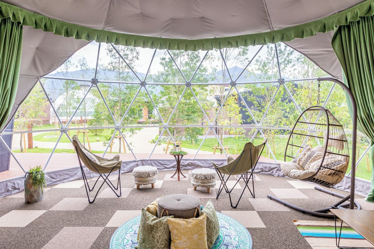 A tent with a checkered floor, cushioned seating, and a view of greenery outside.