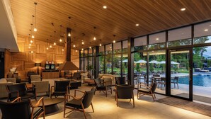 Un espace de détente intérieur moderne, avec un plafond en bois et de grandes fenêtres donnant sur une piscine.
