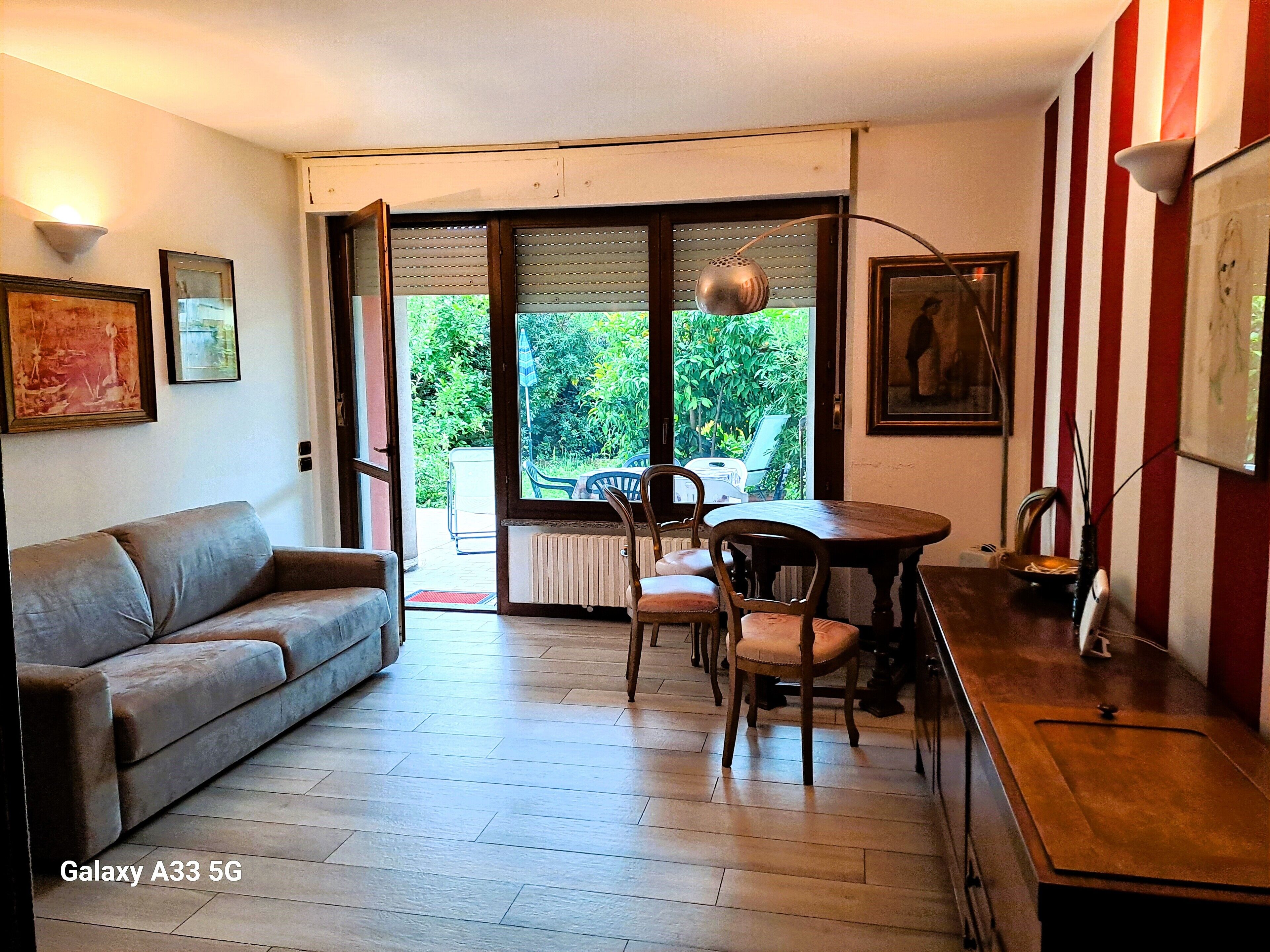 Ein Wohnzimmer mit einer Couch, einem Esstisch mit Stühlen, einem Heizkörper und einem Fenster mit Jalousien.