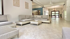 A spacious living room with a large sectional sofa, two side tables, and a decorative wall piece. - Private & spacious riverside home with HUGE pool, 10 mins to Rincon beaches! (Aguada)