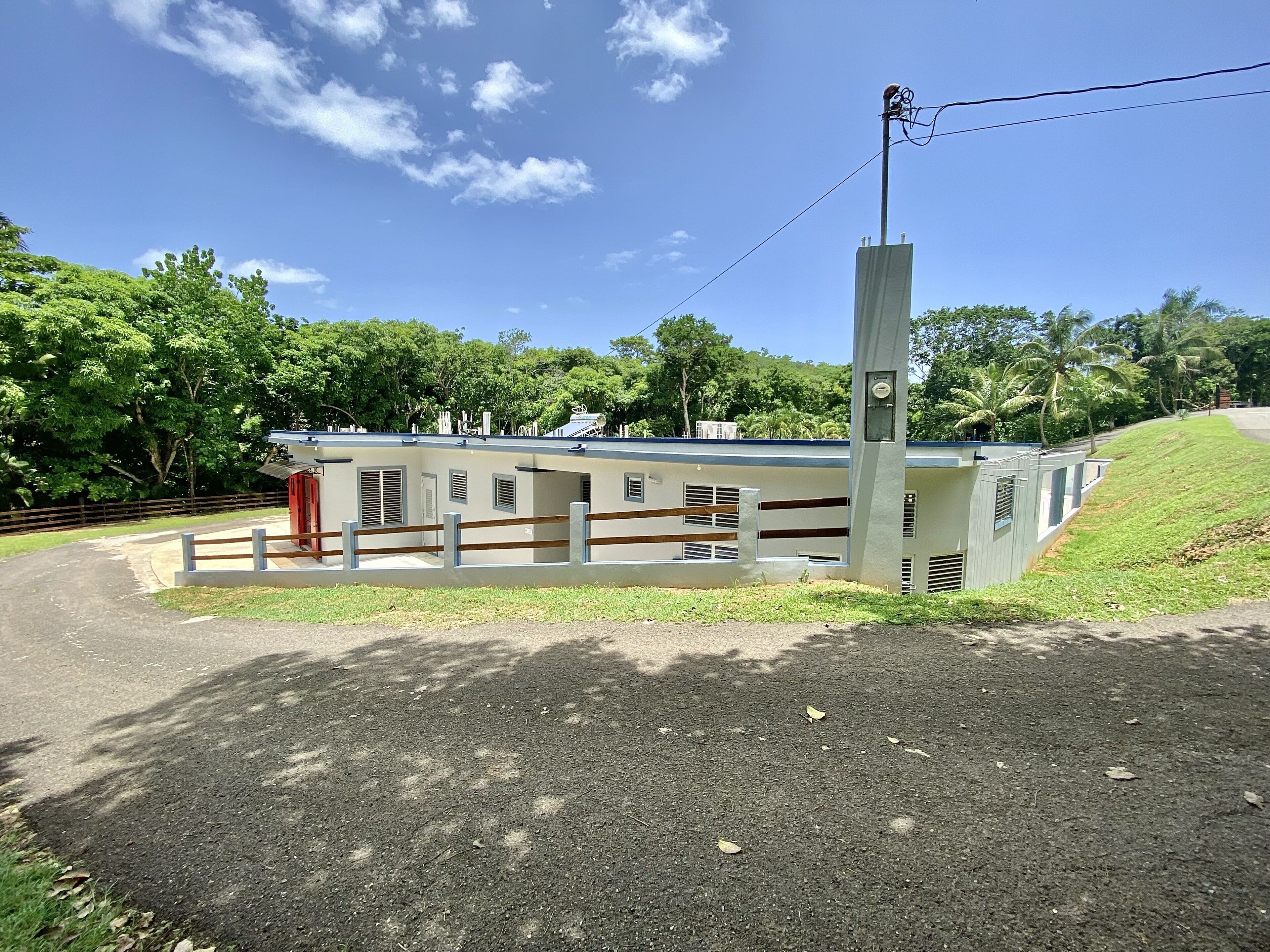 A building with a flat roof, a fenced area, and a utility pole with wires.