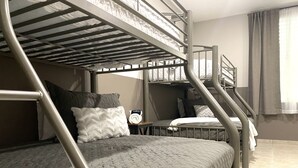 A bunk bed room with a metal ladder, a small table with a clock, and a window with curtains. - Private & spacious riverside home with HUGE pool, 10 mins to Rincon beaches! (Aguada)