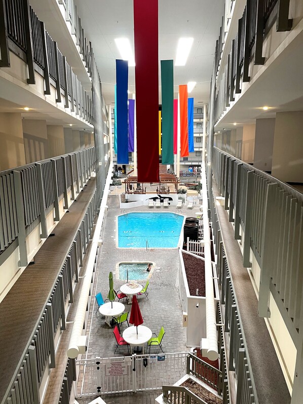 A multi-level indoor swimming pool area with a central pool, smaller pools, and a seating area with tables and chairs.