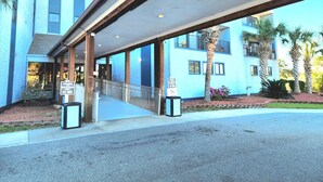 En hotellentrél med en överbyggd gångväg, palmer och en skylt som anger ett fritt utrymme på 3 meter.