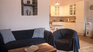 Een gezellige woonkamer met een donkerblauwe bank, een houten salontafel en een stenen boog boven een plank.